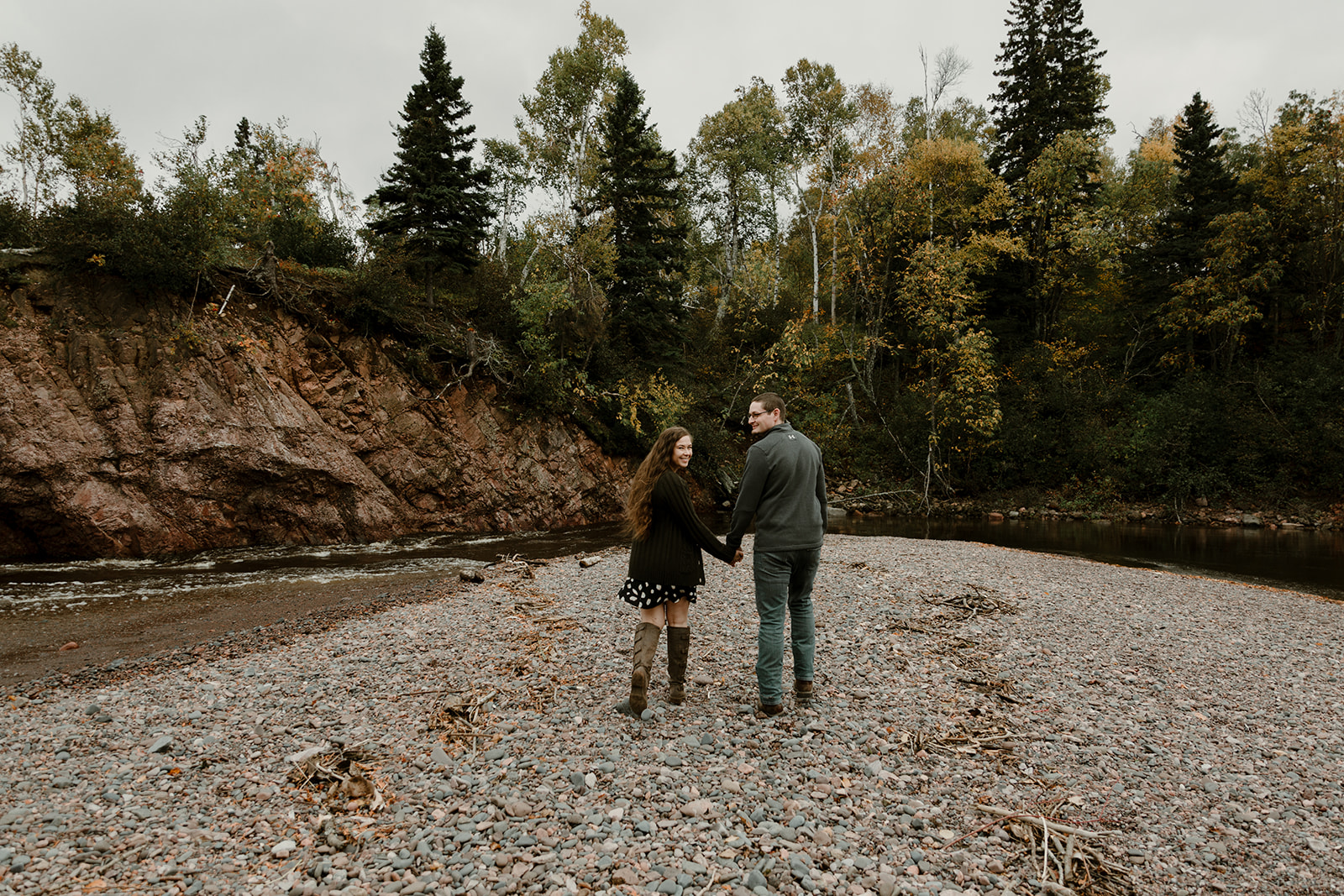 Couple walking hand in hand on beach at Tettegouche State Park